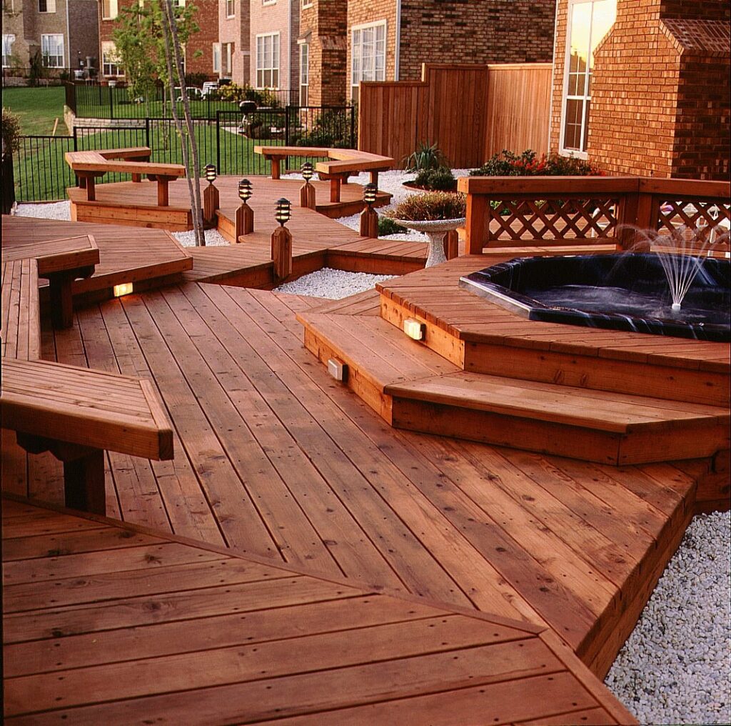 large stained wood deck with built-in benches, steps, lattice railing, and a sunken hot tub